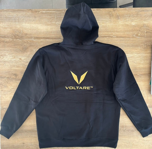 Actual black Voltare hoodie sample laid flat, showing the gold V and VOLTARE wordmark embroidery below the hood.