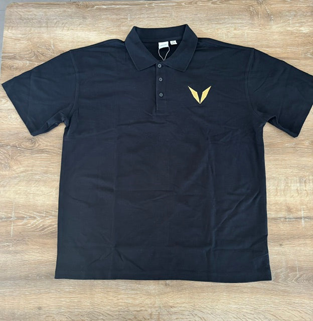 Actual black Voltare polo sample laid flat, showing the collar, button placket and gold V embroidery on the left chest.