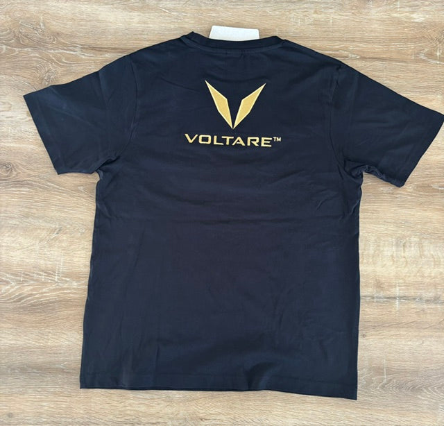 Actual black Voltare tee sample laid flat from behind, showing the gold V and VOLTARE wordmark embroidery below the collar.
