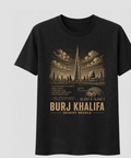 Front of the Black Voltare Burj Khalifa Desert Needle tee, featuring gold-toned tower and Dubai skyline artwork above historical facts, a location map, coordinates and Burj Khalifa Desert Needle lettering