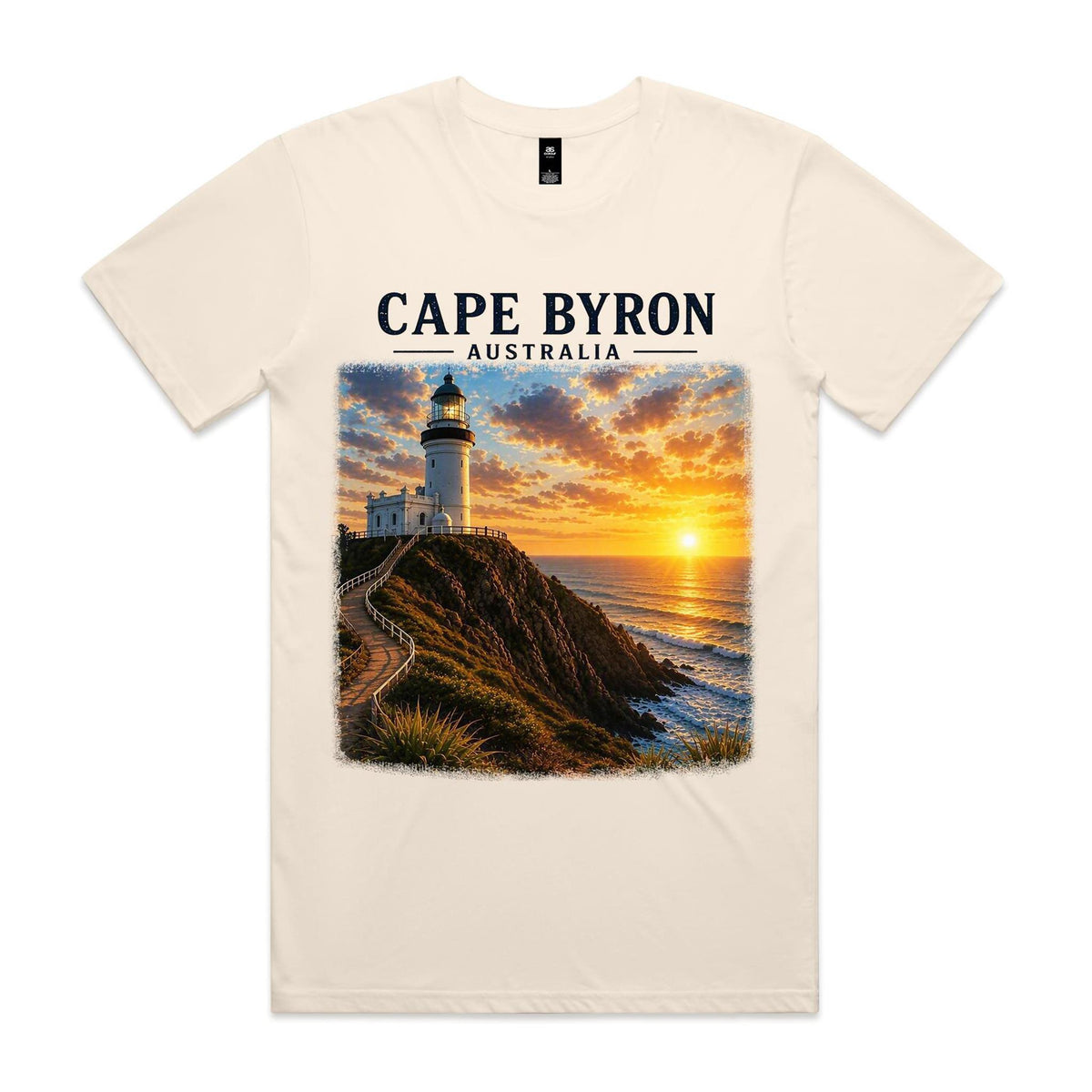 Ecru Voltare Cape Byron tee featuring a lighthouse above a rocky coast with golden ocean light beneath Cape Byron Australia lettering